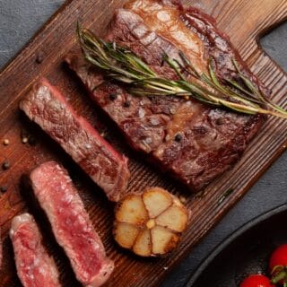 Grilled steak and vegetables on wooden board.