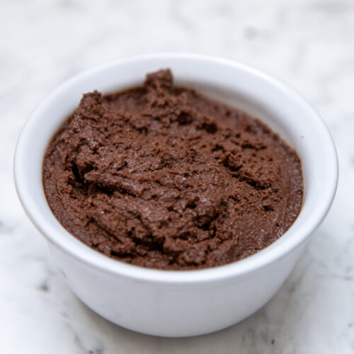 Bowl of homemade keto chocolate mousse on marble surface